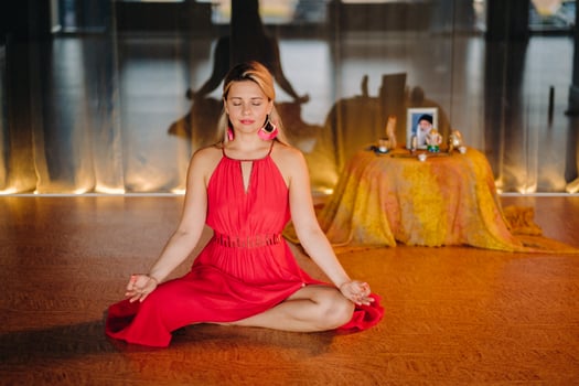 Meditation and concentration. a woman in a red dress, sitting on the floor with her eyes closed, is practicing medicine indoors. Peace and relaxation photo