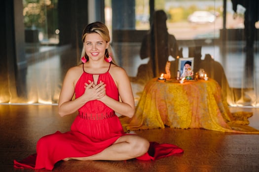Meditation and concentration. a woman in a red dress sitting on the floor is practicing medicine indoors . Calm and relaxation photo