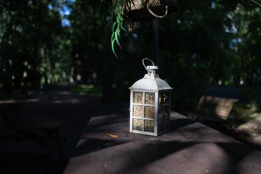 A beautiful decoration in the form of a large lantern and candlestick stands on a table illuminated photo