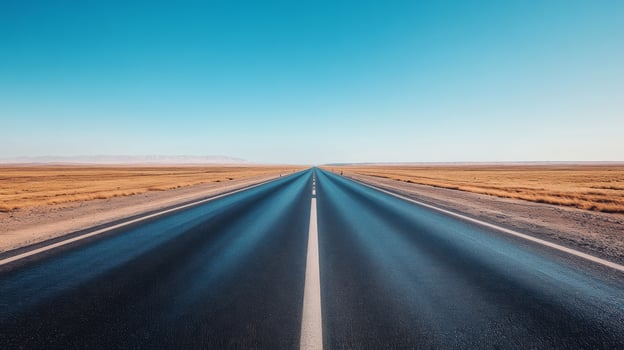 A wide-angle shot of an empty highway stretching into the horizon under a clear blue sky photo