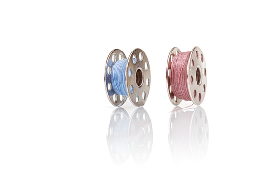 spools of blue and pink thread on a white background photo
