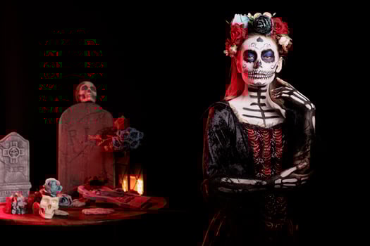 Woman dressed in Day of the Dead horror costume with flower headband celebrating Dia de los Muertos. Girl wearing scary skeleton corpse makeup promoting Mexican culture during Halloween photo