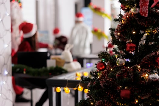 Stylishly decorated Christmas tree close up with employees receiving special gifts from Santa Claus on winter holidays in blurred background. Xmas costumed manager giving red box presents to workers photo