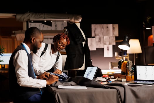African american suitmakers working with premium quality fabrics in professional tailoring studio. Coworkers making exquisite garments following sketch designs of upcoming sartorial collection photo