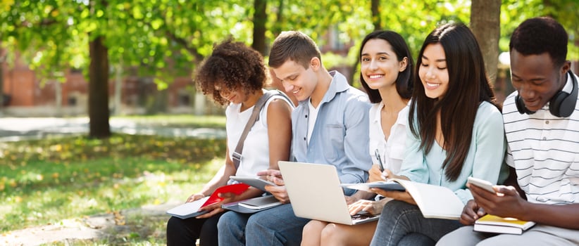 Group of international students preparing for classes together in university courtyard, smiling and enjoying summer weather photo