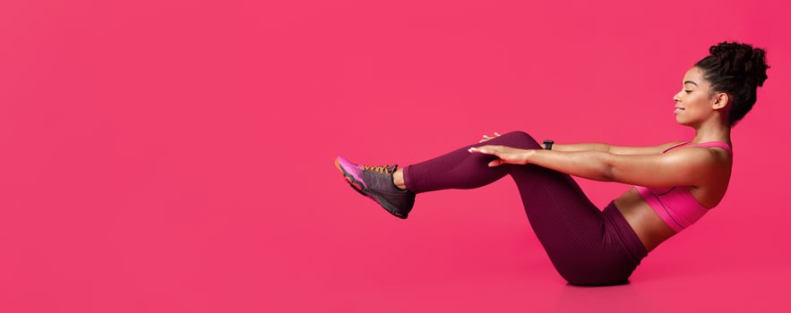 Young sporty afro woman practicing over red background doing crisscross exercise, bicycle crunches pose sitting on floor, copy space photo