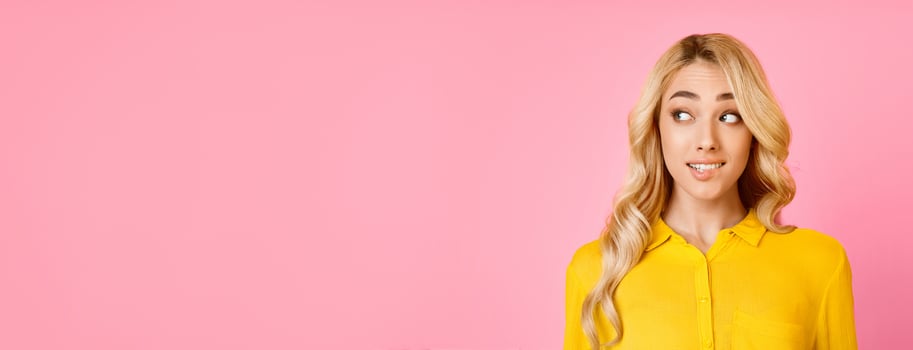 The image shows a young woman with long, blonde hair looking to the side. She is wearing a yellow shirt and has a thoughtful expression on her face. The background is a solid pink, copy space photo