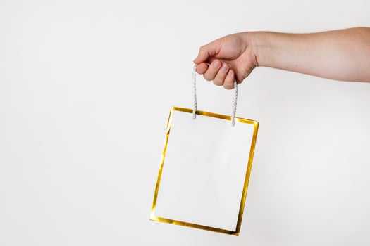 A Caucasian person holding a gift bag with a gold border, perfect for Christmas shopping or festive celebrations photo