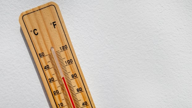 Wooden thermometer displaying high temperature in Celsius and Fahrenheit, representing heatwave and climate change issues photo