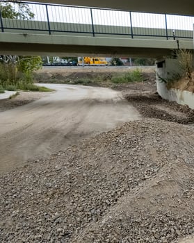Underpass construction zone with gravel piles and machinery representing infrastructure development and roadwork challenges photo