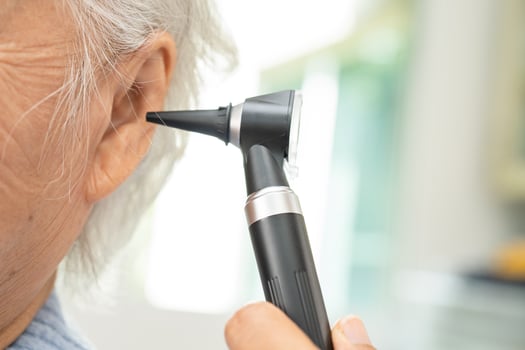 Audiologist or ENT doctor use otoscope checking ear of asian senior woman patient treating hearing loss problem. photo