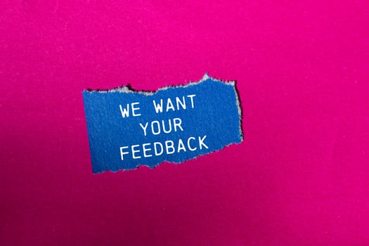 We want your feedback message written on ripped blue torn paper piece on pink background. Conceptual we want your feedback symbol. Copy space. photo