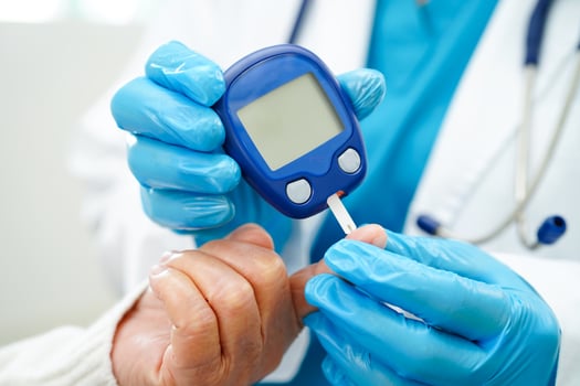 Asian doctor using digital glucose meter for check sample blood sugar level to treatment diabetes. photo