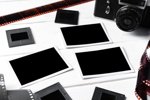 Old retro camera and photos on white wooden background