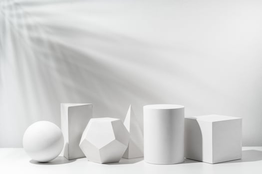 A collection of white geometric shapes arranged on a table in a bright studio setting photo