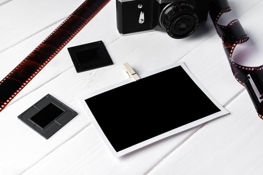 Old retro camera and photos on white wooden background