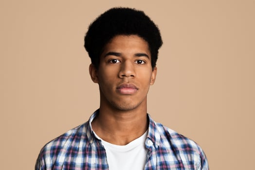 Serious african-american guy portrait on white background, teenager looking at camera photo