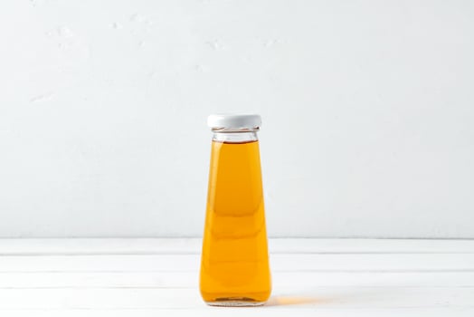 Small glass bottle of fresh juice on white background photo
