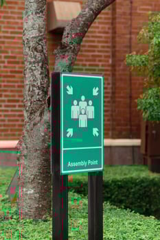 An assembly point sign ensures safety during emergencies, guiding people to a designated gathering area. photo