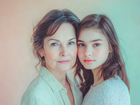 Portrait of a mature woman and a young adult woman, standing close together, both looking serene and elegant against a pastel background photo