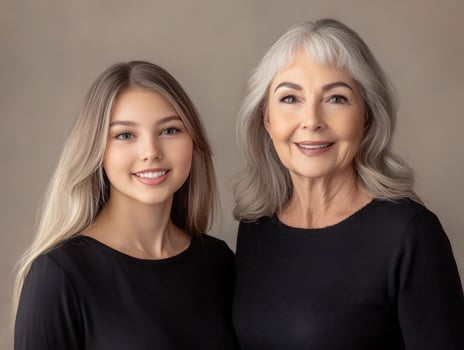 Portrait of two beautiful women, one younger and one older, standing side by side, smiling, with a soft neutral background photo