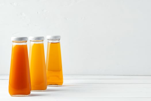 Glass bottles of different juices on white background photo