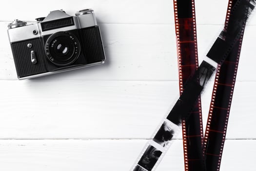 Old retro camera and photos on white wooden background