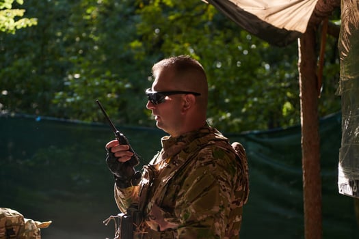 A military major employs a Motorola radio for seamless communication with his fellow soldiers during a tactical operation, showcasing professionalism and strategic coordination photo