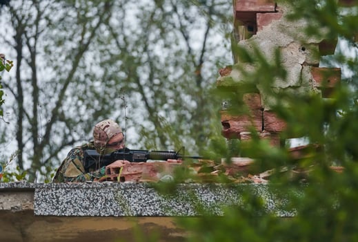 An elite soldier, camouflaged and stealthily navigating through dangerous woodland terrain, executes a covert mission in a secluded forest area photo