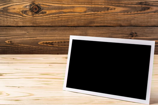 Blank photo frame on brown wooden background