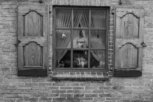 A black and white photo of a window with shutters