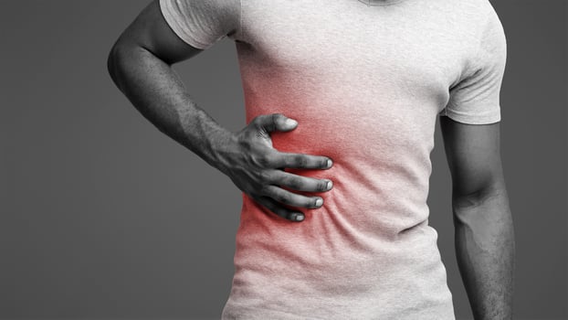 Black guy holding his side, suffering from acute liver pain, cropped photo