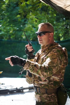 A military major employs a Motorola radio for seamless communication with his fellow soldiers during a tactical operation, showcasing professionalism and strategic coordination photo