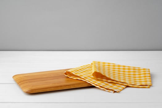 Wooden cutting board on cotton napkin on white wooden table photo