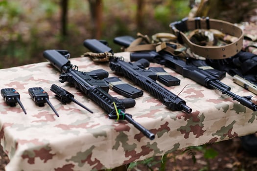 An array of military weapons, including rifles and pistols, is meticulously arranged on a table in a military base, presenting a close-up view of the diverse firepower and armament meticulously photo