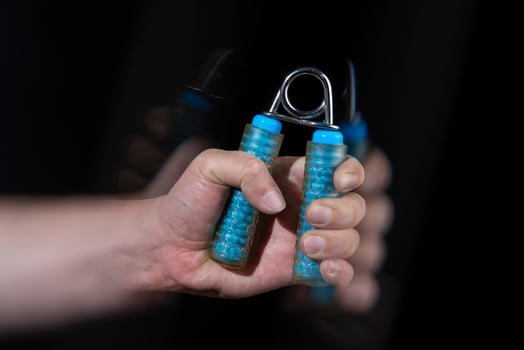 Close-up of man's hand exercising with a blue spring dumbbell with motion effect photo