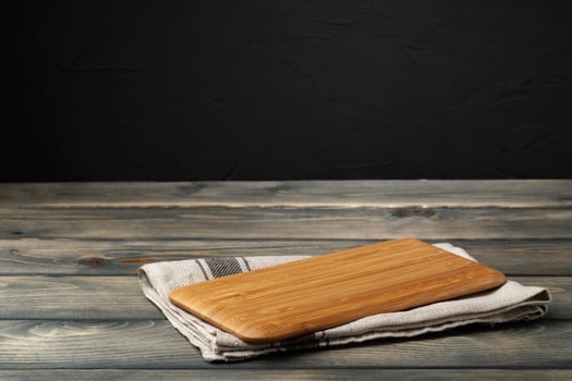 Wooden board with kitchen napkin on dark wooden table photo