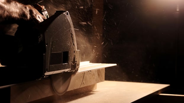 Close-up of a man cuts a wooden plank with an electric circular saw in a workshop. Cutting a piece of wood on a circular saw in backlight. Ideal topics related carpentry, efficient sawing techniques photo