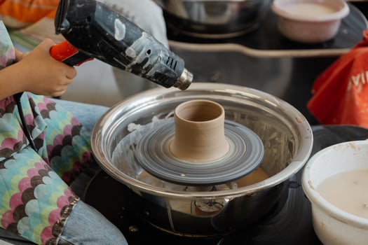 A student shapes pottery on a wheel during a ceramics class in the studio photo