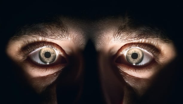 Close-up of a person's intense, wide-open eyes illuminated by dramatic lighting, creating a sense of fear, surprise, or curiosity. photo