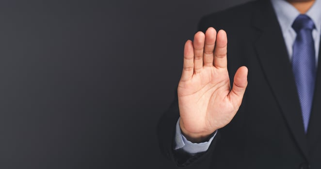 Businessman making stop gesture with his hands while standing on gray background. photo