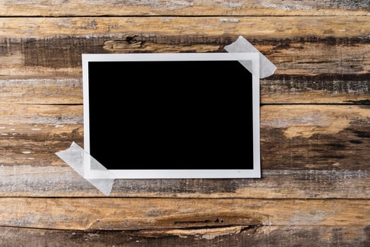 Paper blank photo frames hanging on wooden wall
