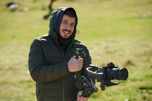 A skilled videographer, equipped with professional gear, captures the essence of nature's beauty, expertly documenting the scenic landscape in a cinematic masterpiece that reflects the seamless blend photo