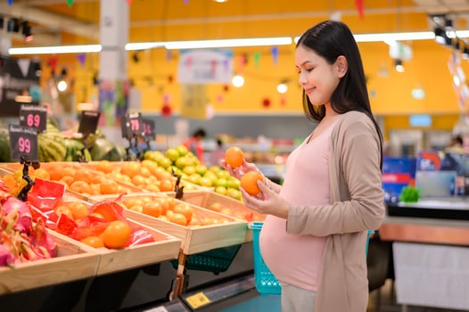 Beautiful pregnant woman shopping healthy food at grocery shop photo