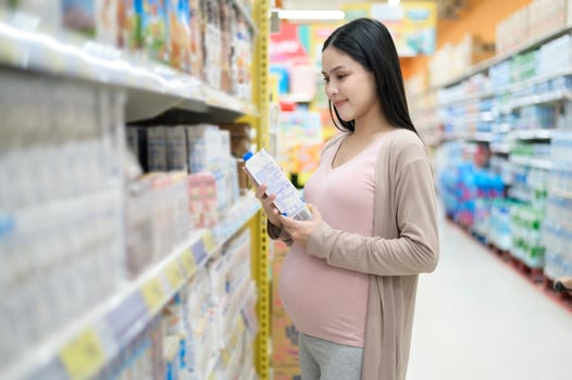 Beautiful pregnant woman shopping milk at grocery shop photo