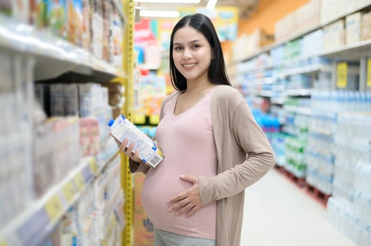 Beautiful pregnant woman shopping milk at grocery shop photo