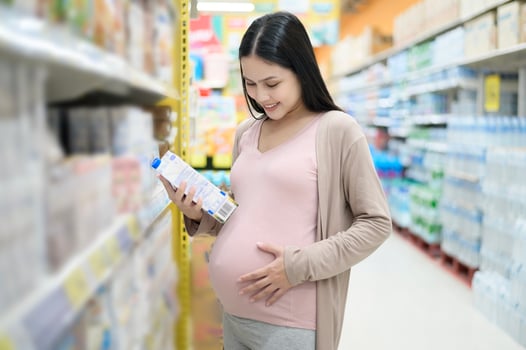 Beautiful pregnant woman shopping milk at grocery shop photo