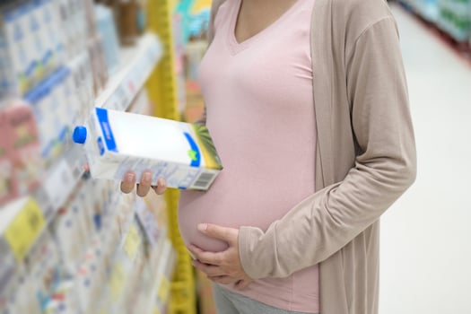Beautiful pregnant woman shopping milk at grocery shop photo