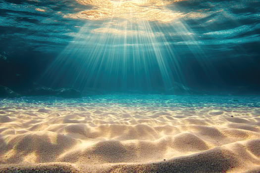 Sun shining on idyllic sandy seabed underwater ocean scene photo