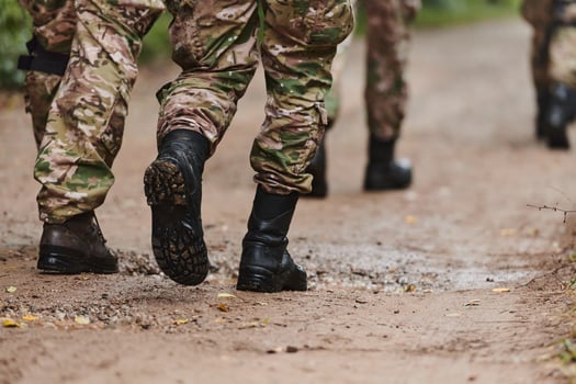 Close up photo, the resilient legs of elite soldiers, clad in camouflage boots, stride purposefully along a hazardous forest path as they embark on a high-stakes military mission photo